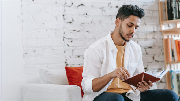 Image of a man sitting on a chair flipping through a journal