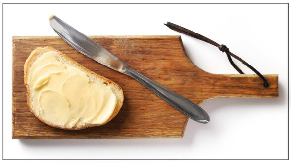 Image of a wooden cutting board with buttered toast and a butter knife on top
