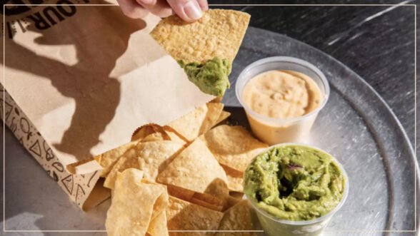 Image of a bag of Chipotle tortilla chips, with a hand scooping guacamole onto a chip