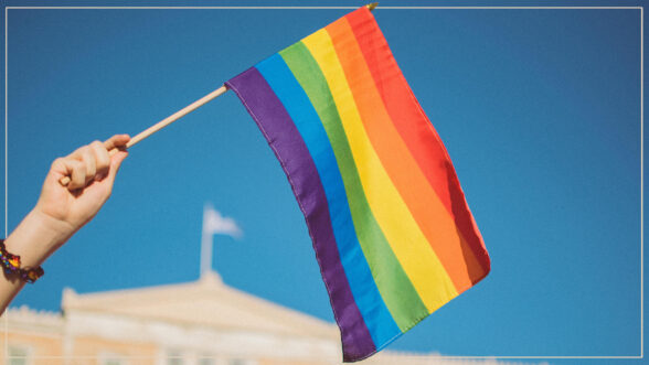 Image of a hand waiving a rainbow pride flag